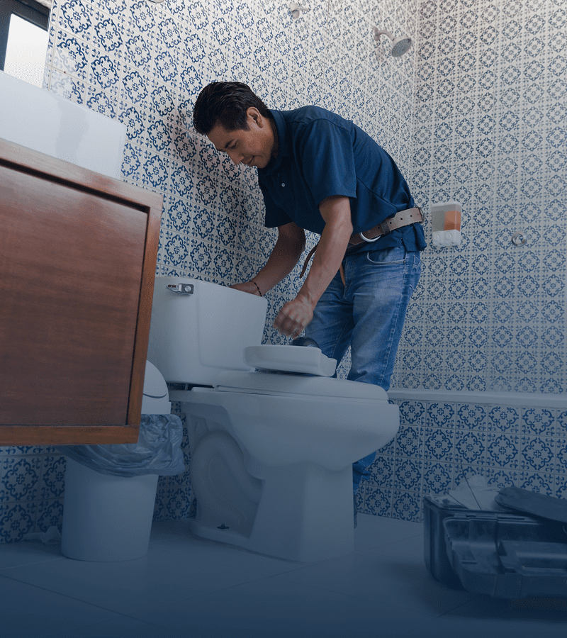 Man repairing toilet in tiled bathroom